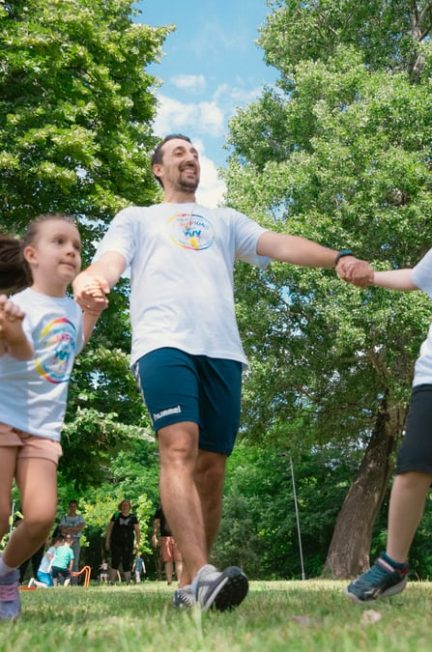 Group of joyful children playing outdoors with an instructor in a sunny park.